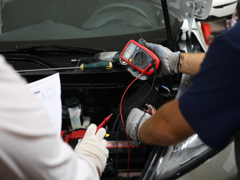Two mechanics testing an auto electric system