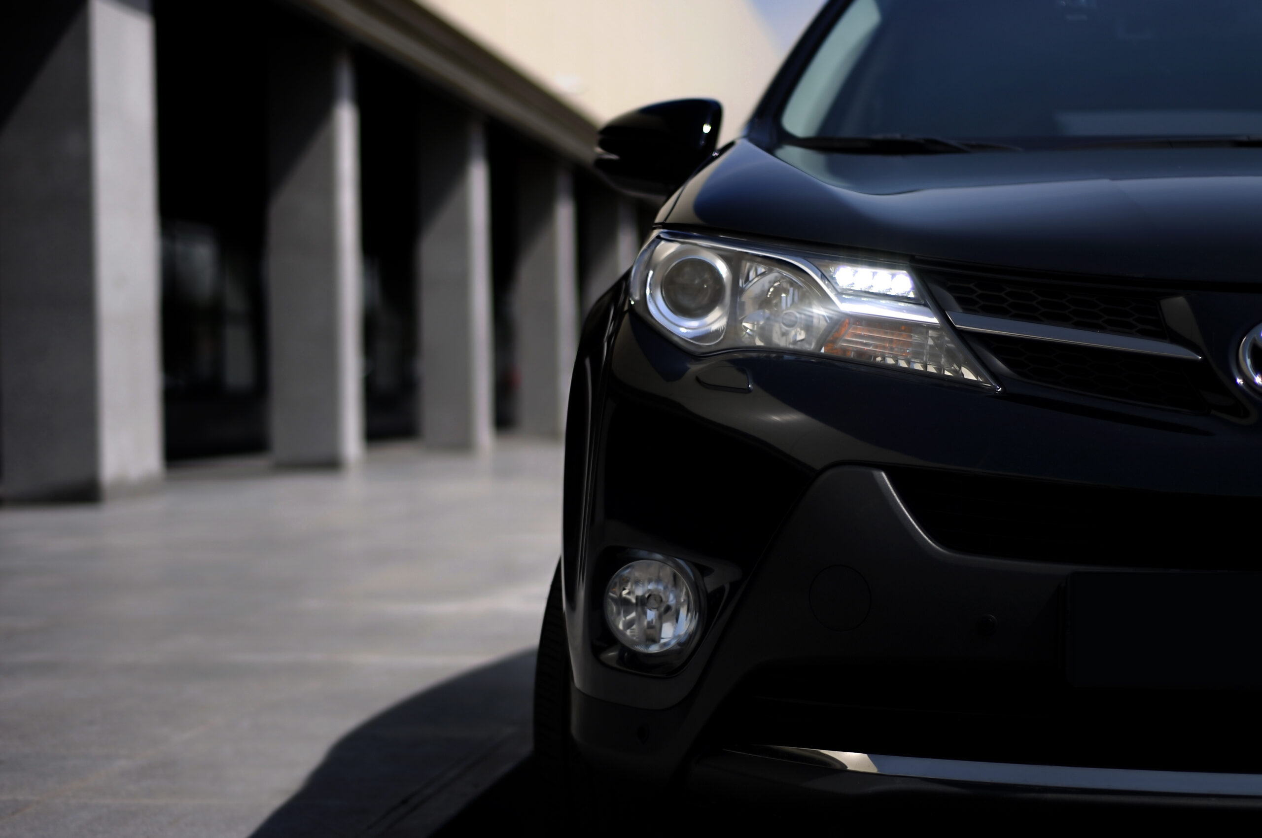 Close-up of black car headlight and front grille