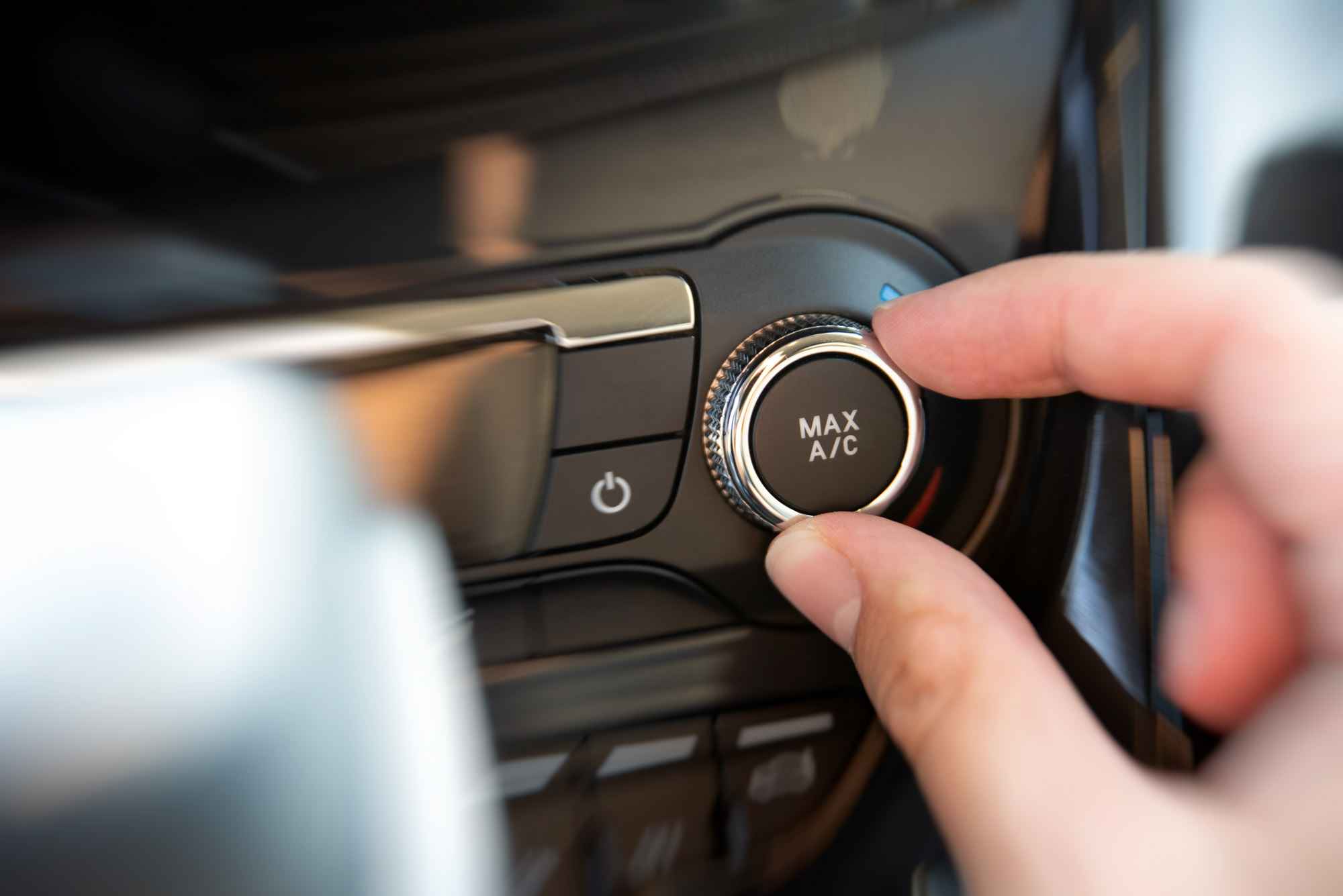 Hand adjusting car air conditioning to max setting