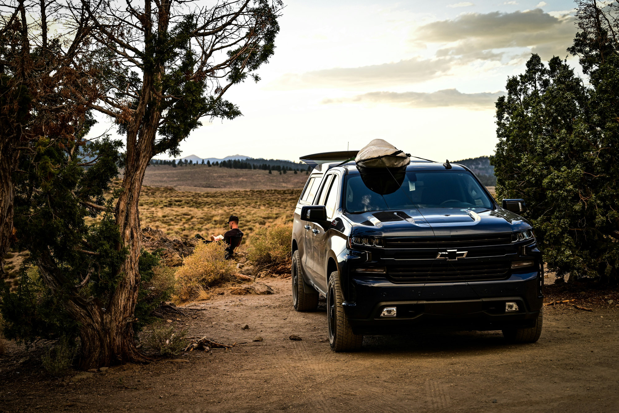 Black pickup truck parked in desert at sunset