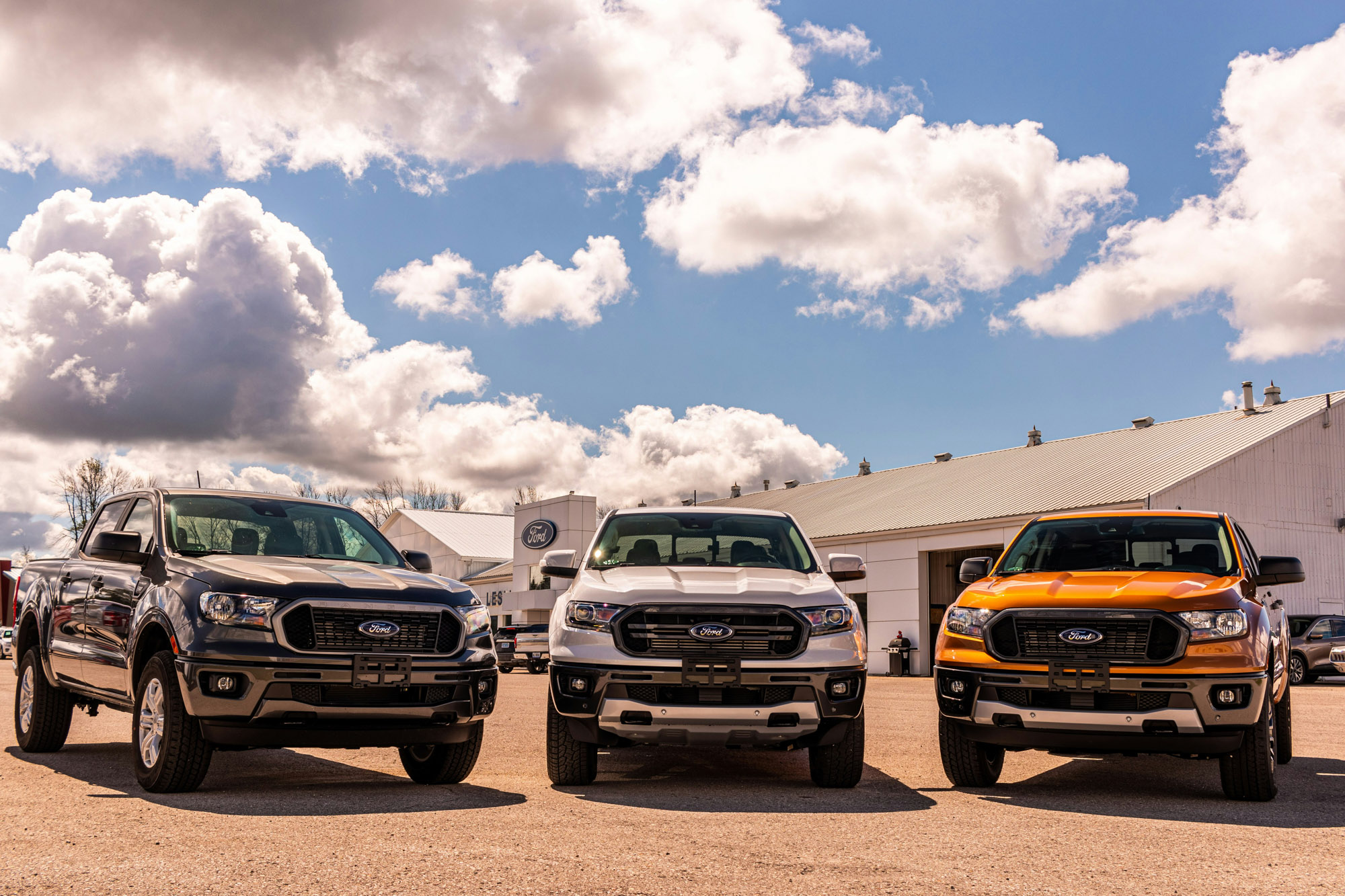 Three Ford pickup trucks parked outside dealership