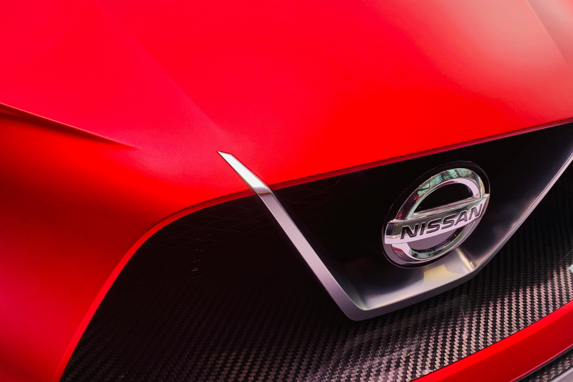 Close-up of red Nissan car grille and emblem