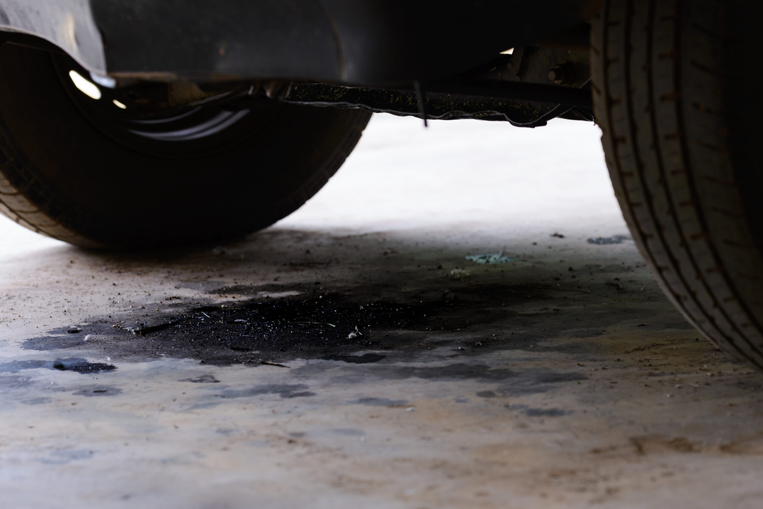 Oil leak puddle under a car on garage floor
