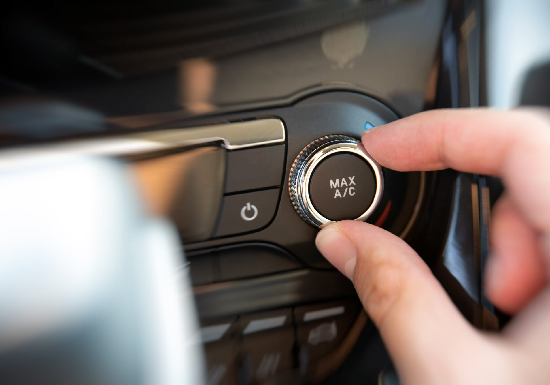 Hand adjusting car air conditioning to max setting