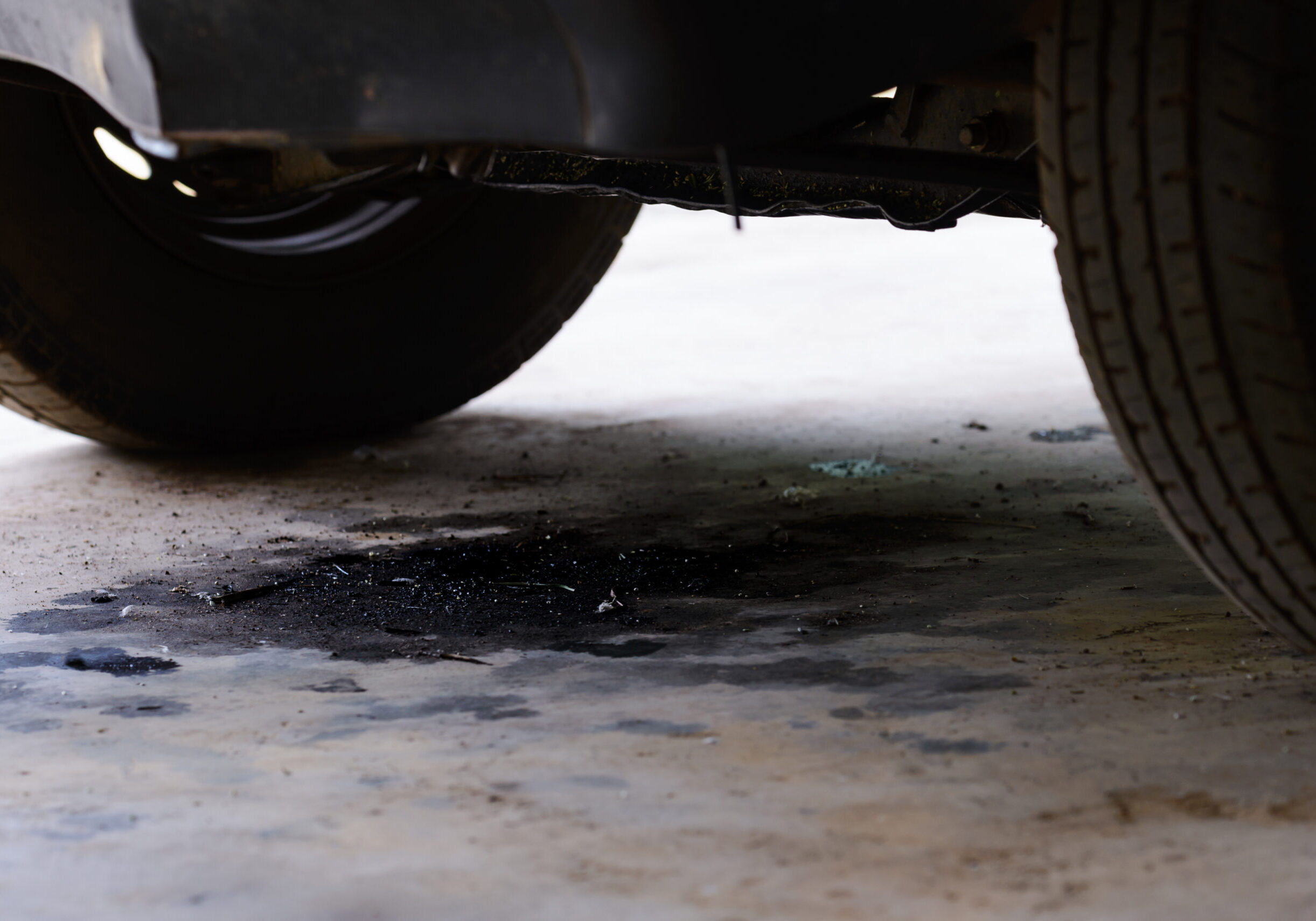 Oil leak puddle under a car on garage floor
